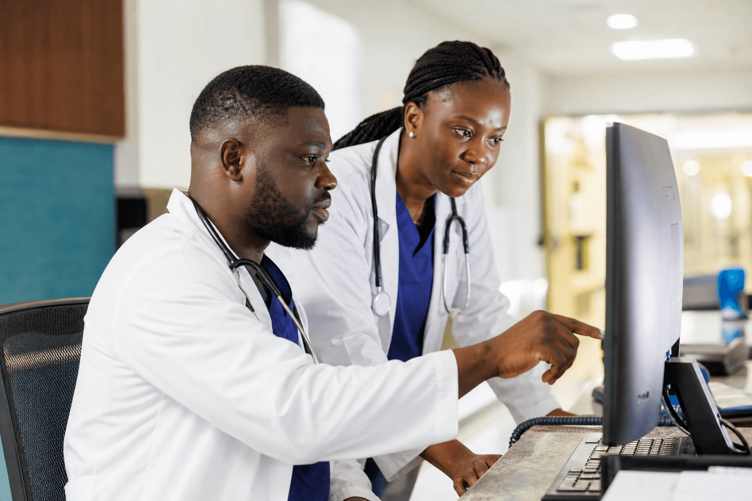 Sierra Leonean doctors reviewing clinical orders together on a monitor
